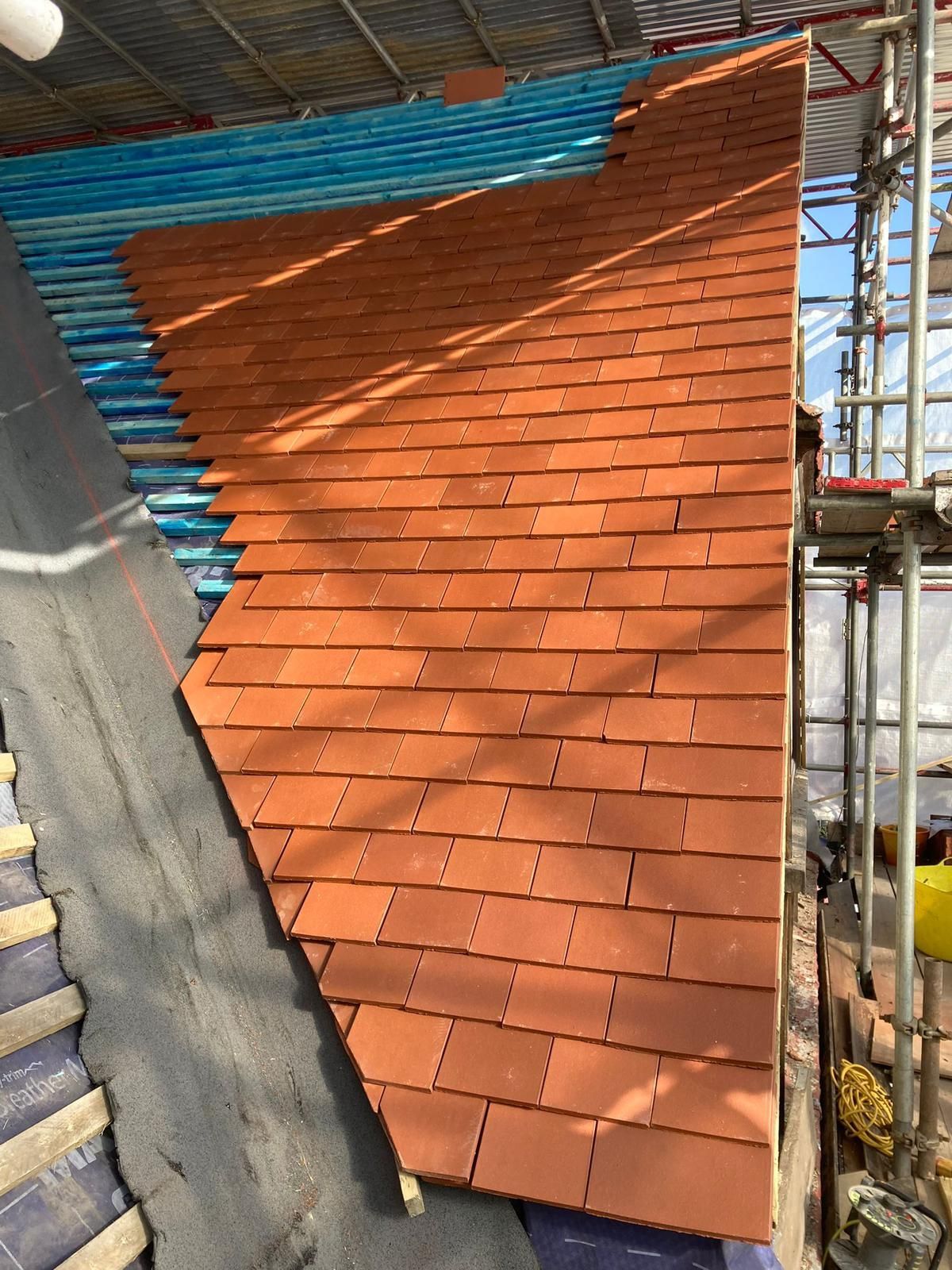 A red tiled roof is being built on top of a building.