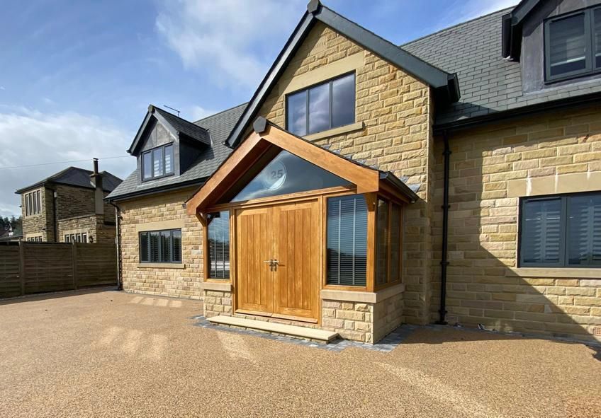 A large brick house with a wooden porch and a driveway in front of it.
