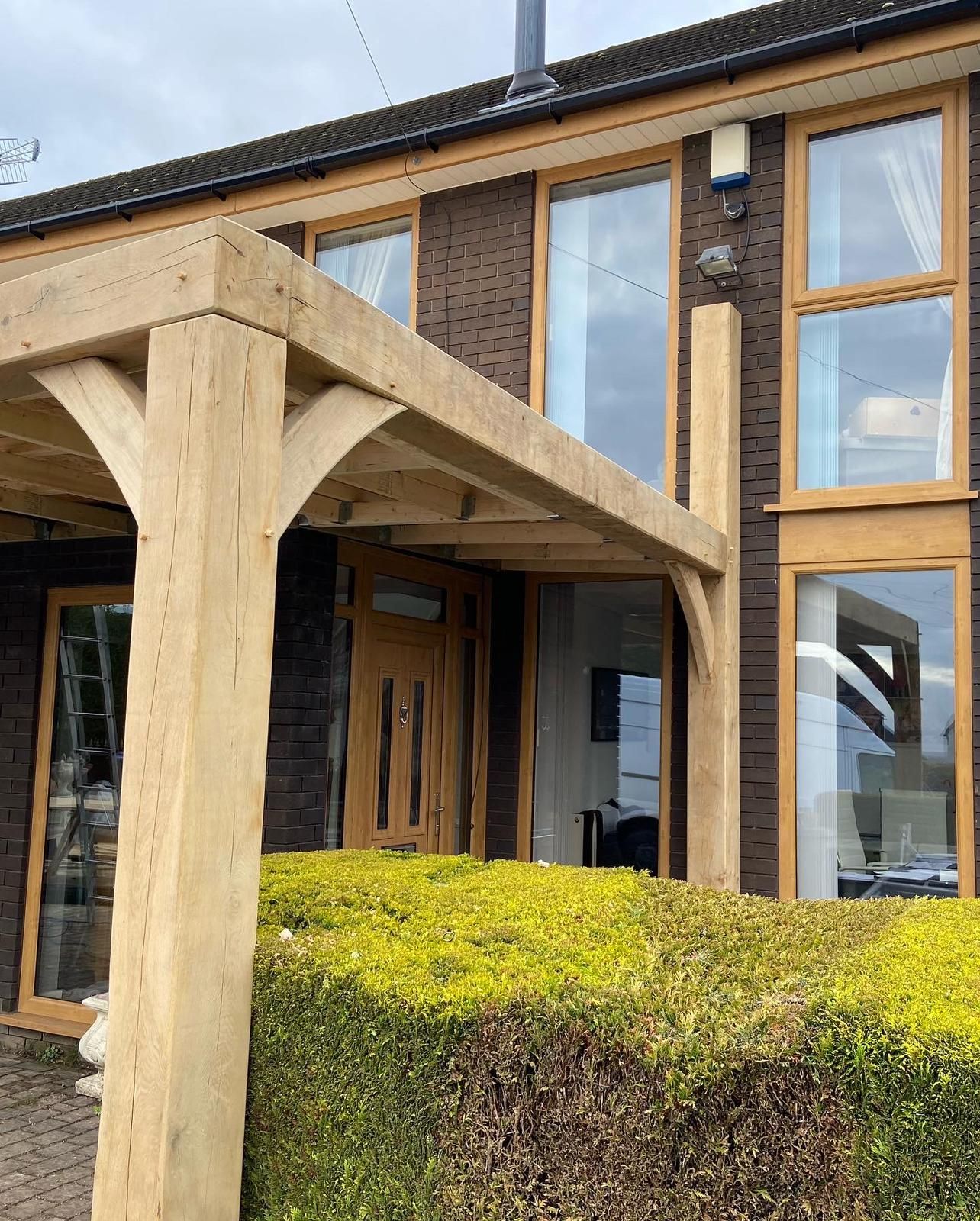 A large house with a wooden pergola in front of it.