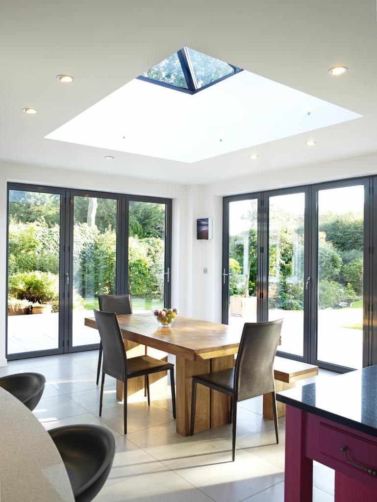 A dining room with a table and chairs and a skylight in the ceiling.