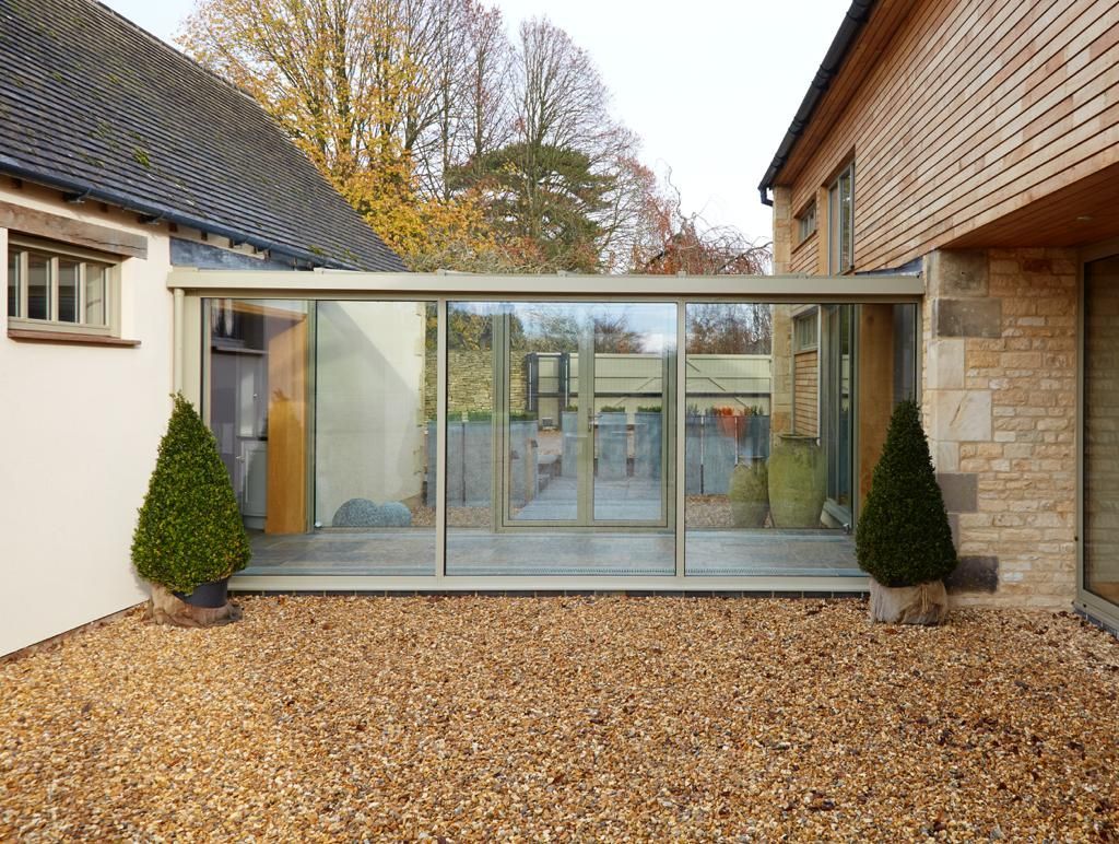 A house with a large glass wall between two buildings.