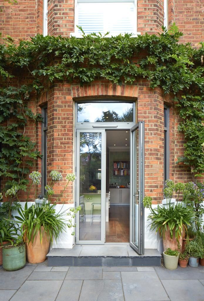 A brick building with a glass door and potted plants in front of it.