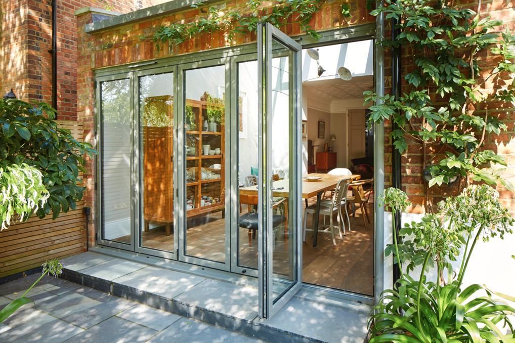 A brick building with a large glass door leading to a dining room.