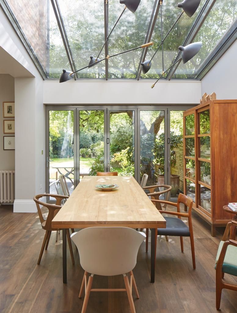A dining room with a table and chairs under a glass ceiling.