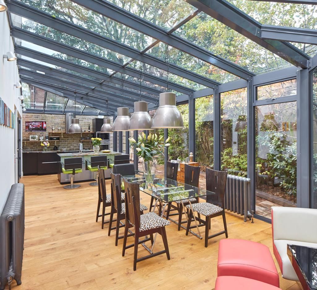 A dining room with a table and chairs under a glass roof.