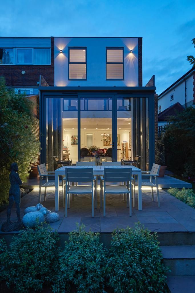 The back of a house with a dining table and chairs in front of it.