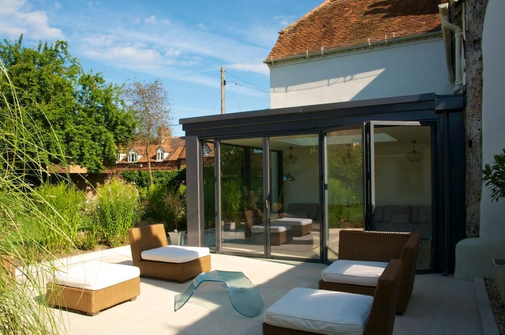 A patio with chairs and ottomans in front of a house