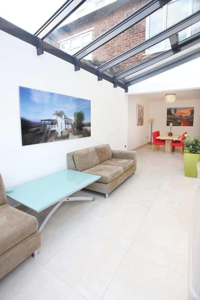 A living room with a couch , table , chairs and a picture on the wall.