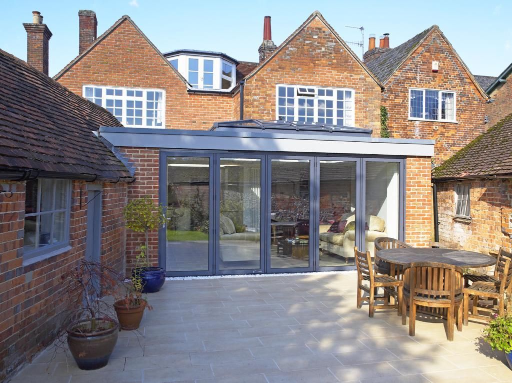 A patio with a table and chairs in front of a brick house