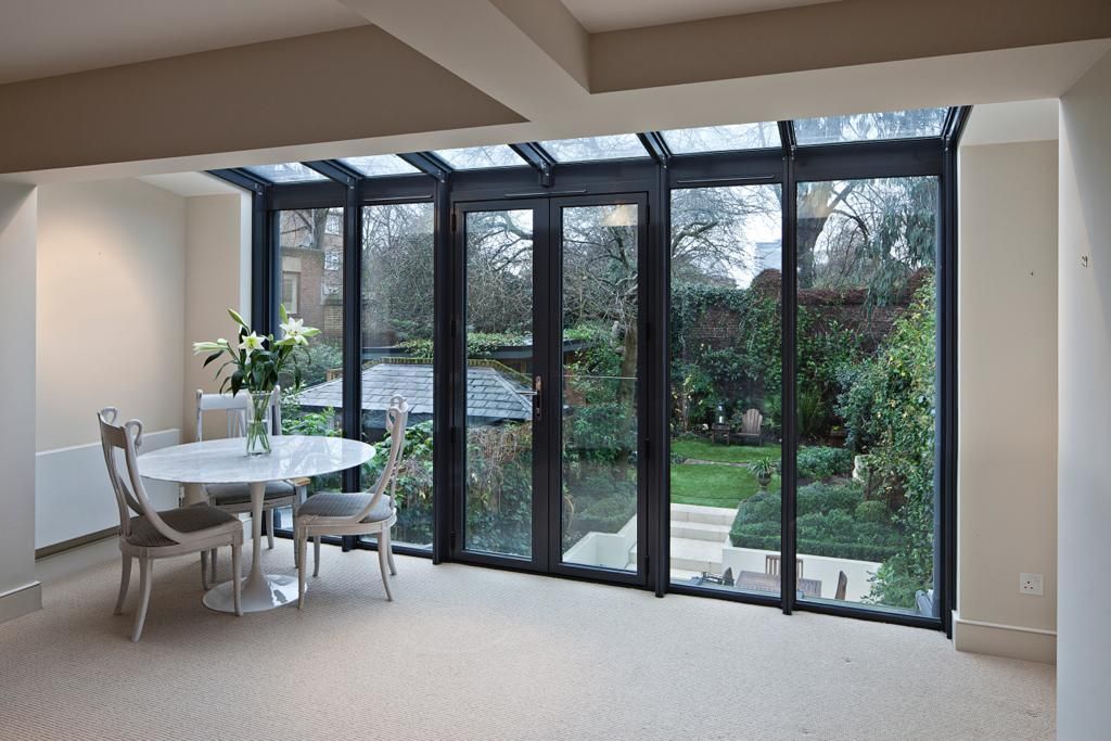 A dining room with a table and chairs and lots of windows