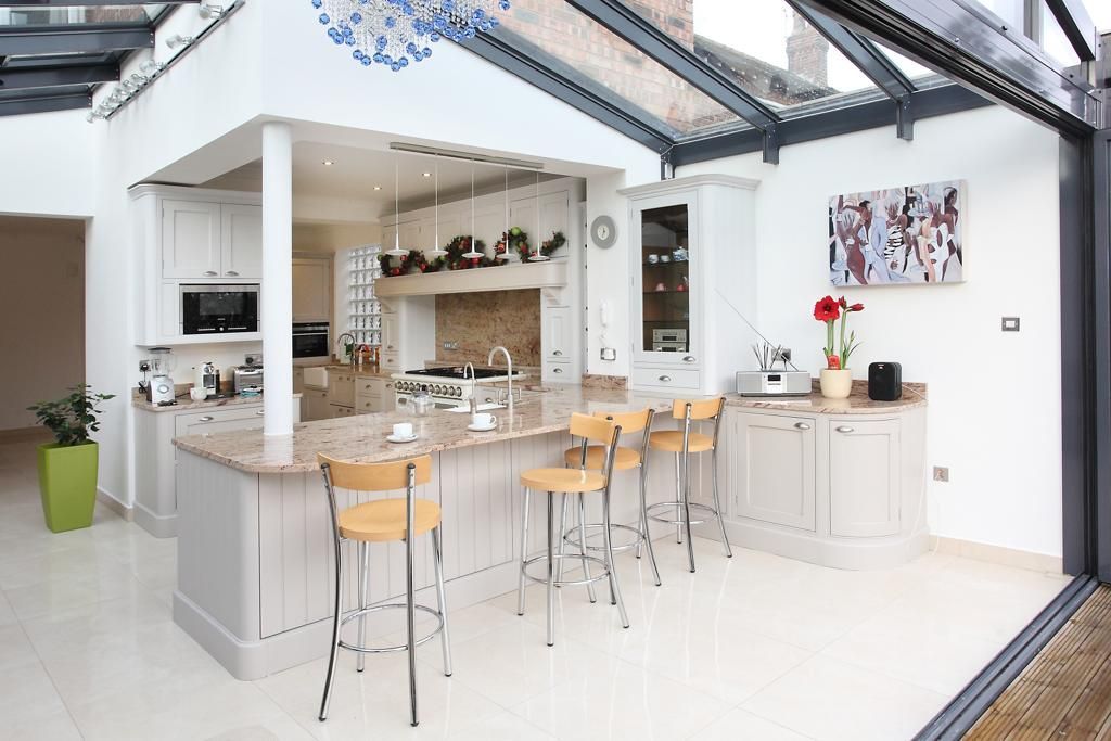 A kitchen with a large island and stools and a glass roof.