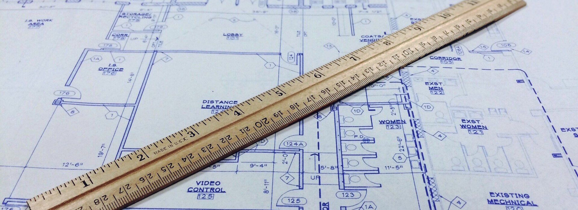 A wooden ruler is laying on top of a blueprint.
