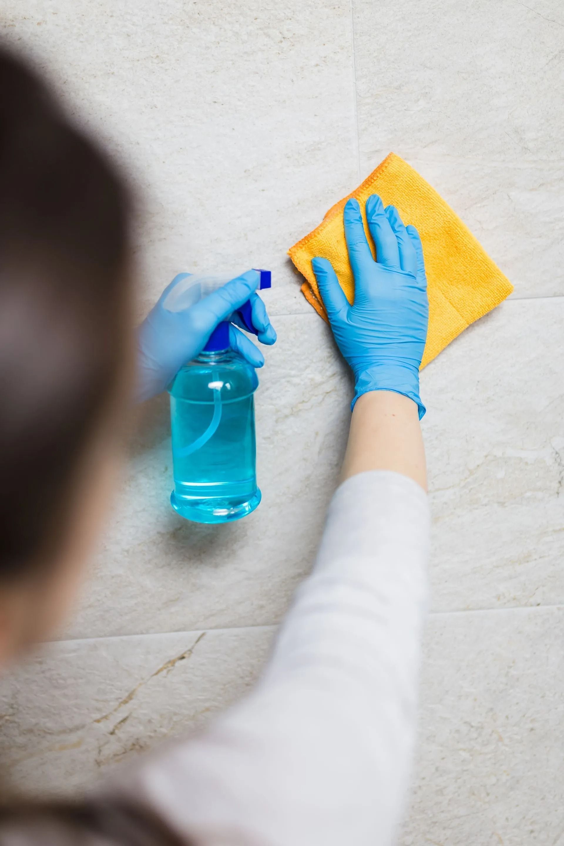 A Woman Is Cleaning the Floor with A Cloth and Spray Bottle