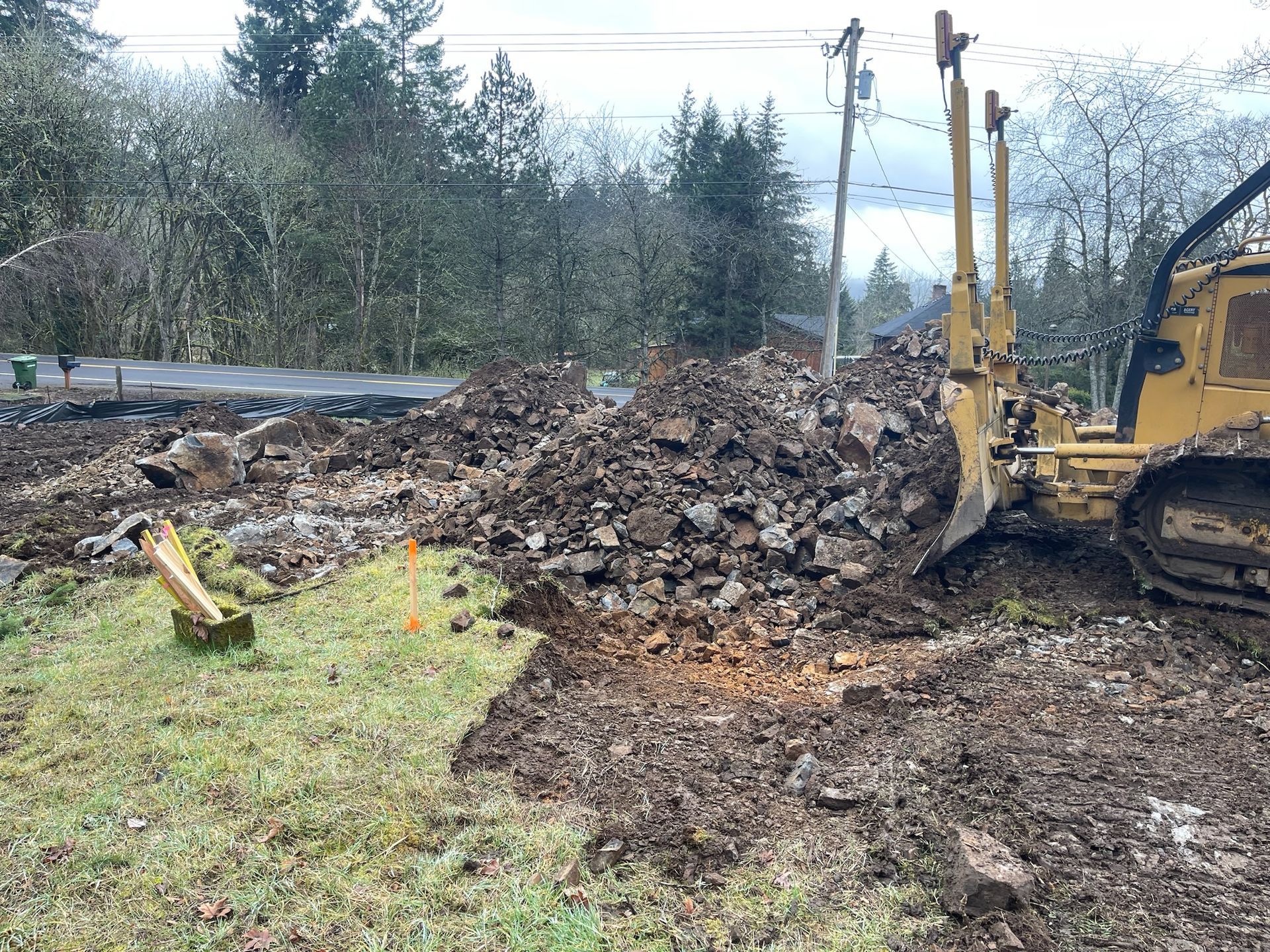 A bulldozer is moving a pile of dirt in a field.