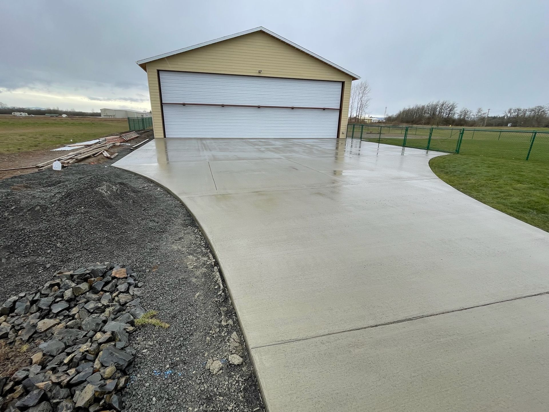 A concrete driveway leading to a garage on a cloudy day.