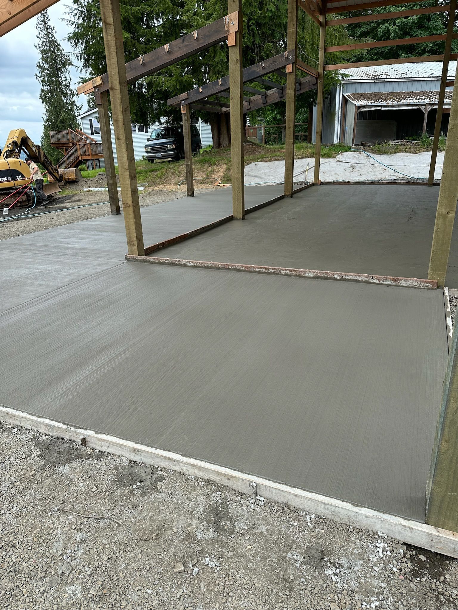 A concrete floor is being poured in front of a wooden structure.