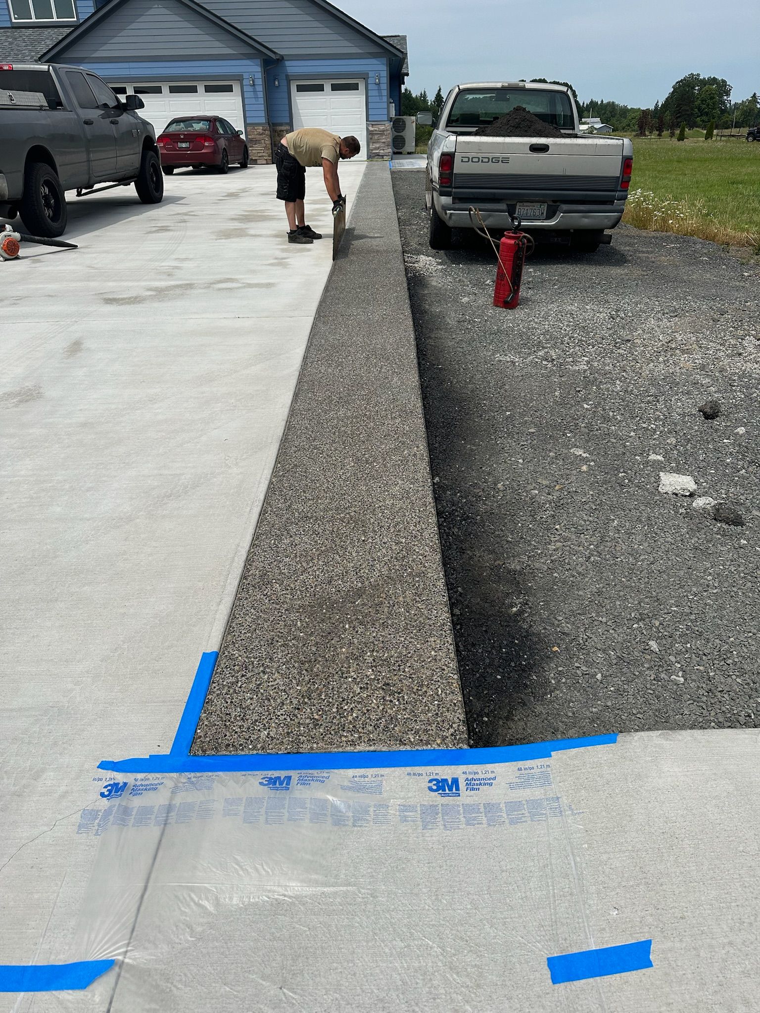 A man is working on a concrete driveway next to a truck.