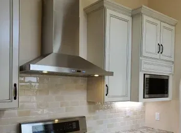 A kitchen with white cabinets , a stove and a microwave.