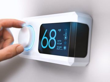 A person is adjusting a thermostat on a wall.