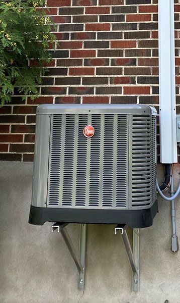 An air conditioner is mounted on the side of a brick building.