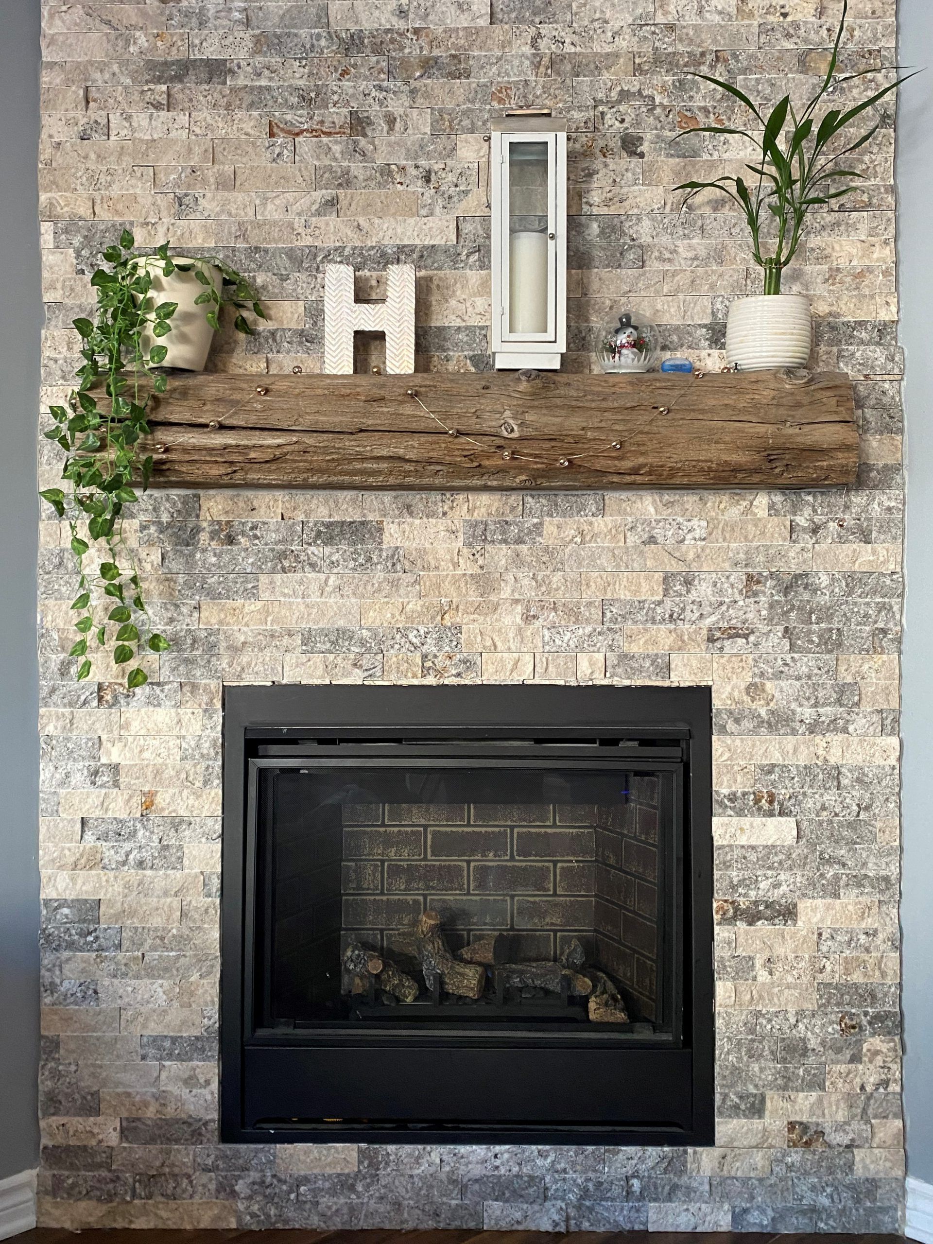 A fireplace with a brick wall and a wooden mantle.