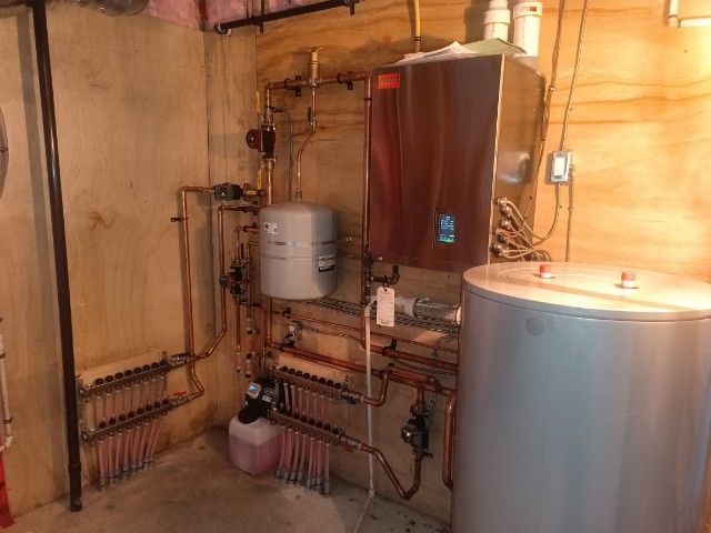 A room with a boiler and a water heater in it.