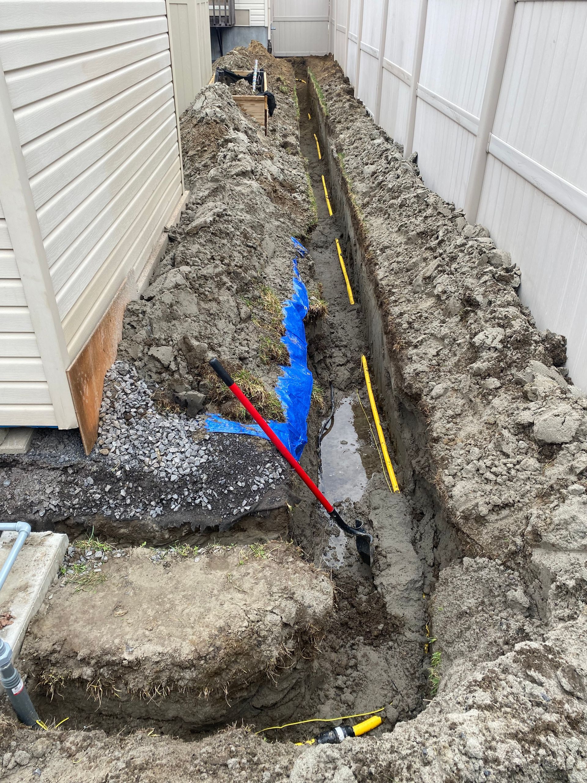 A drainage system is being installed in the backyard of a house.