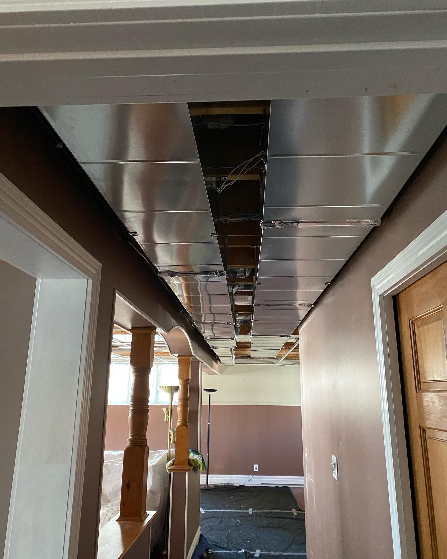 A hallway with a metal ceiling and a wooden door.