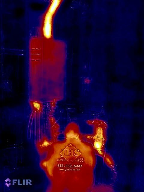 A thermal image of a person standing next to a fire.