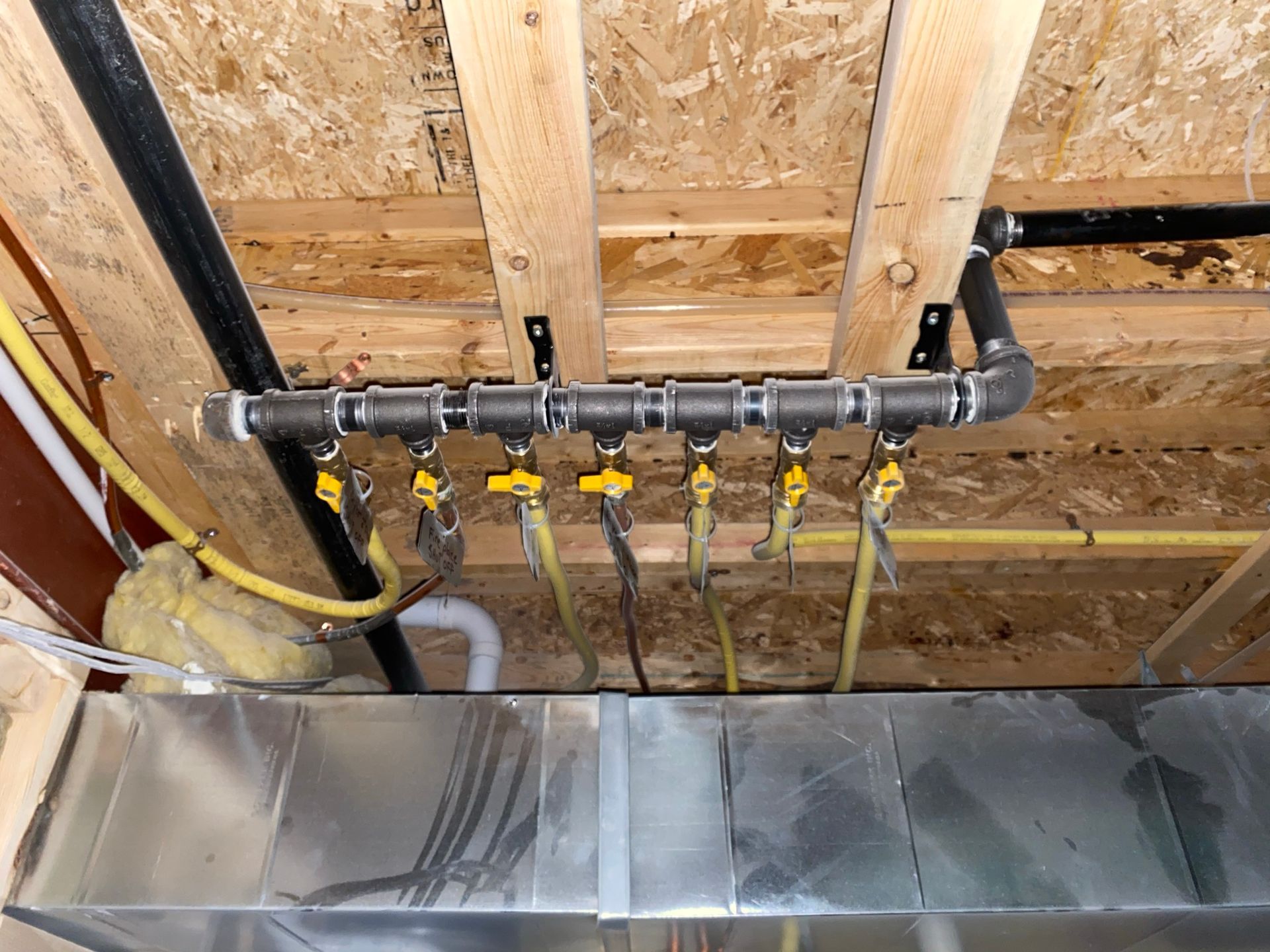 A bunch of pipes are hanging from the ceiling of a house.