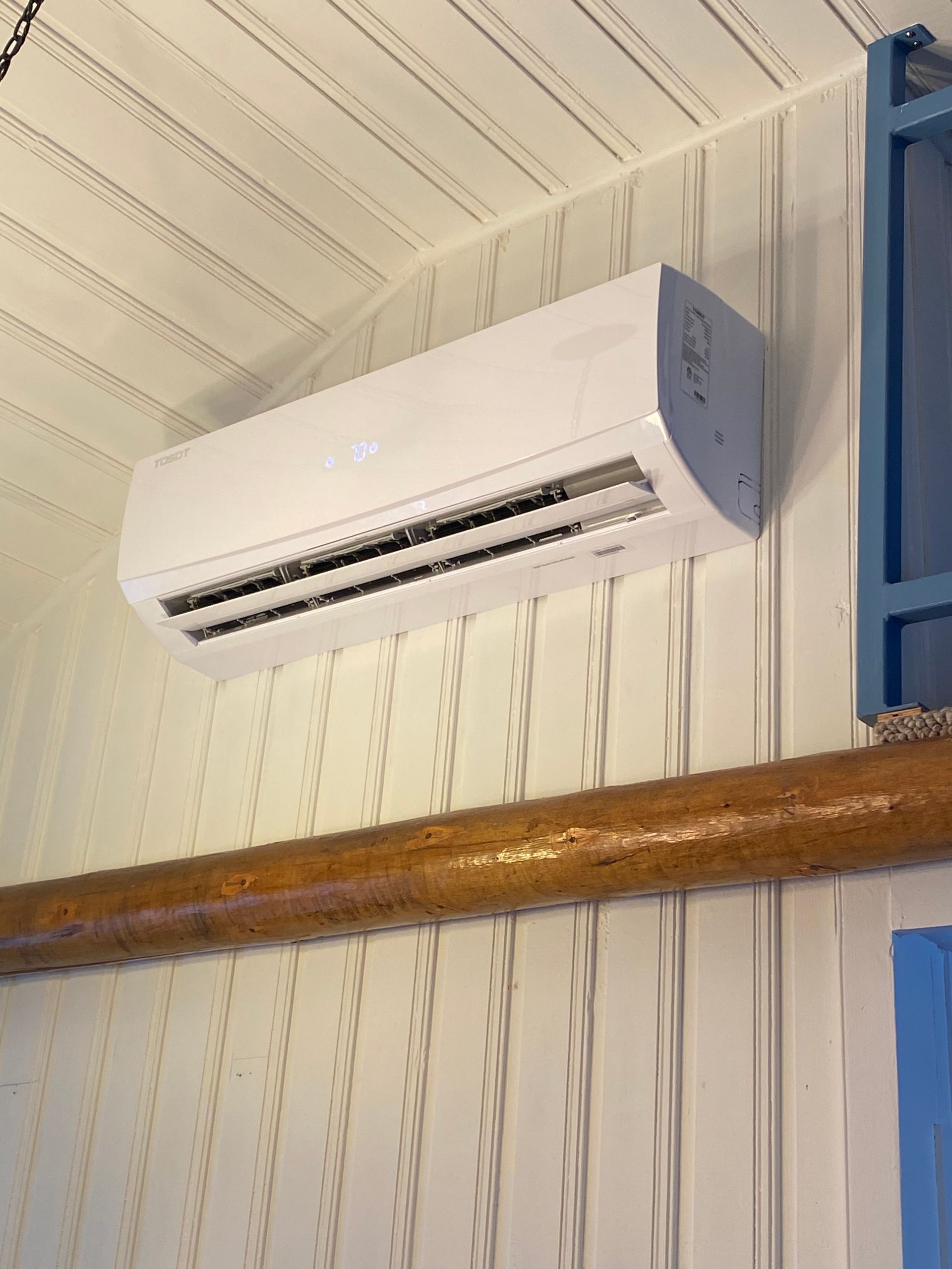 A white air conditioner is hanging from the ceiling of a room.