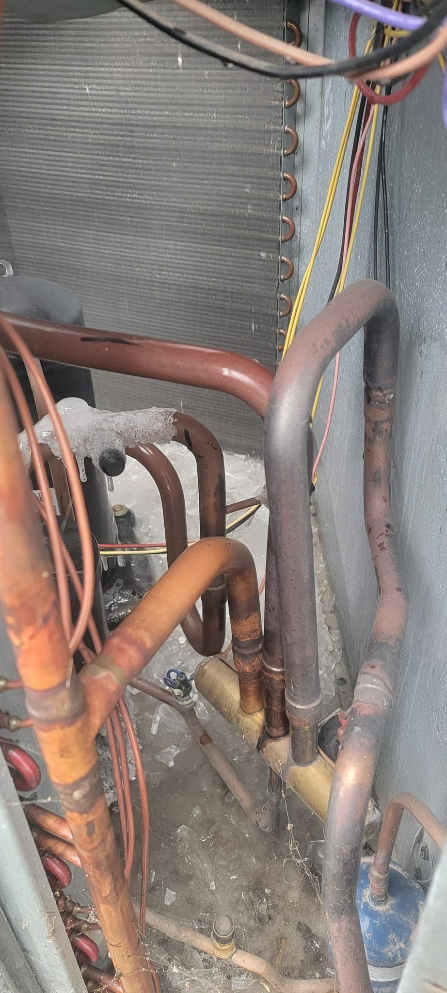 Copper pipes with ice buildup inside an air conditioning unit.