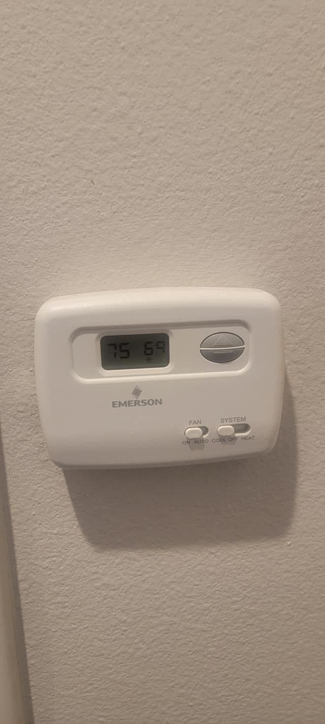 White thermostat on a textured wall; shows 76 degrees.