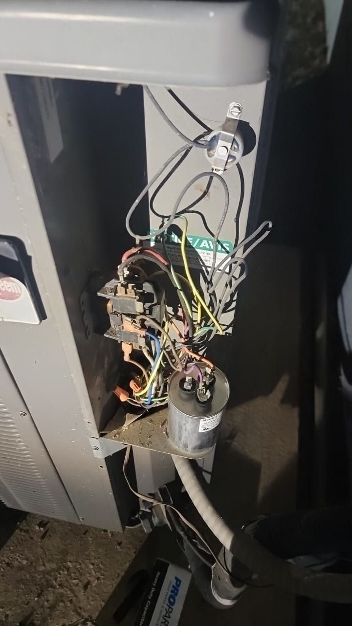 Open air conditioner panel revealing electrical components and wiring.