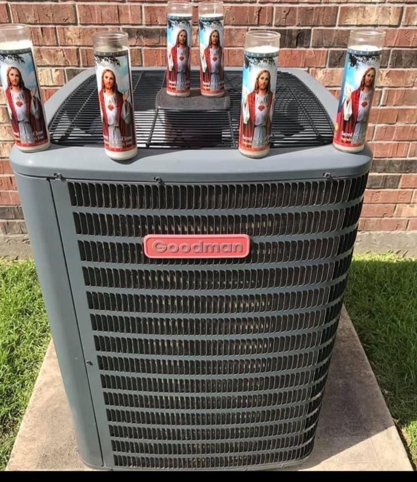 Air conditioner unit with six Jesus candles on top. Outdoors, brick wall background.
