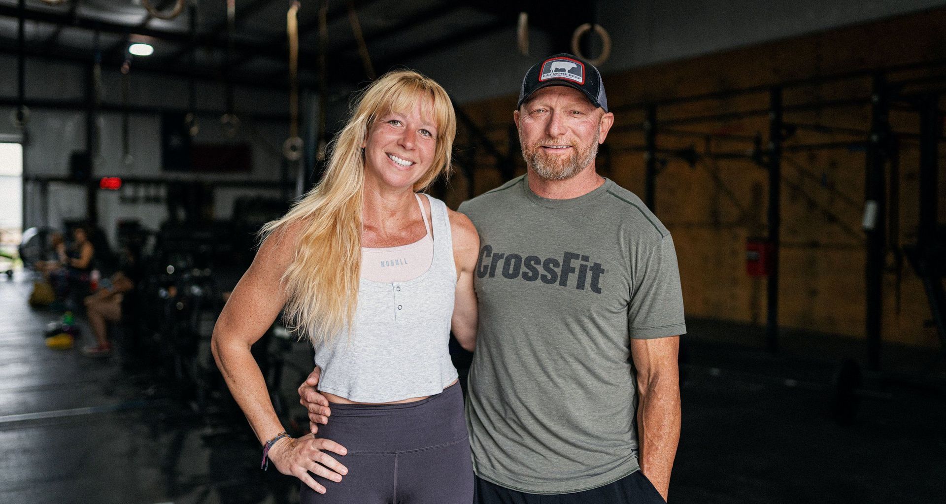 A man and a woman are posing for a picture in a gym.