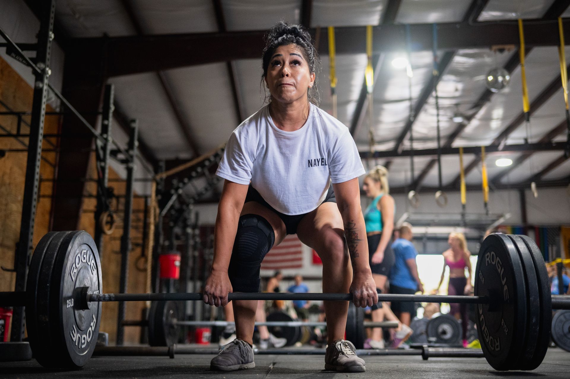 A woman is lifting a barbell in a gym.