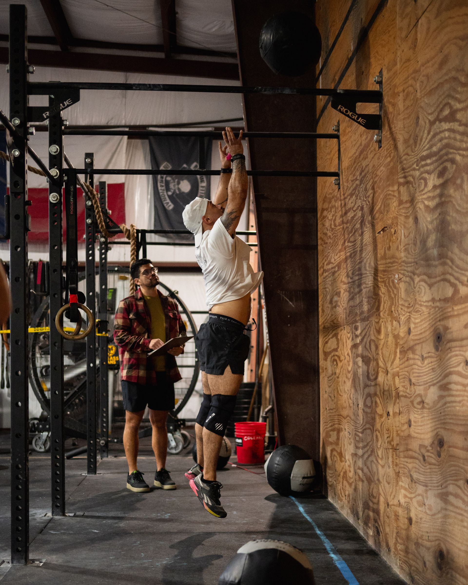 A man is doing a pull up on a bar in a gym.