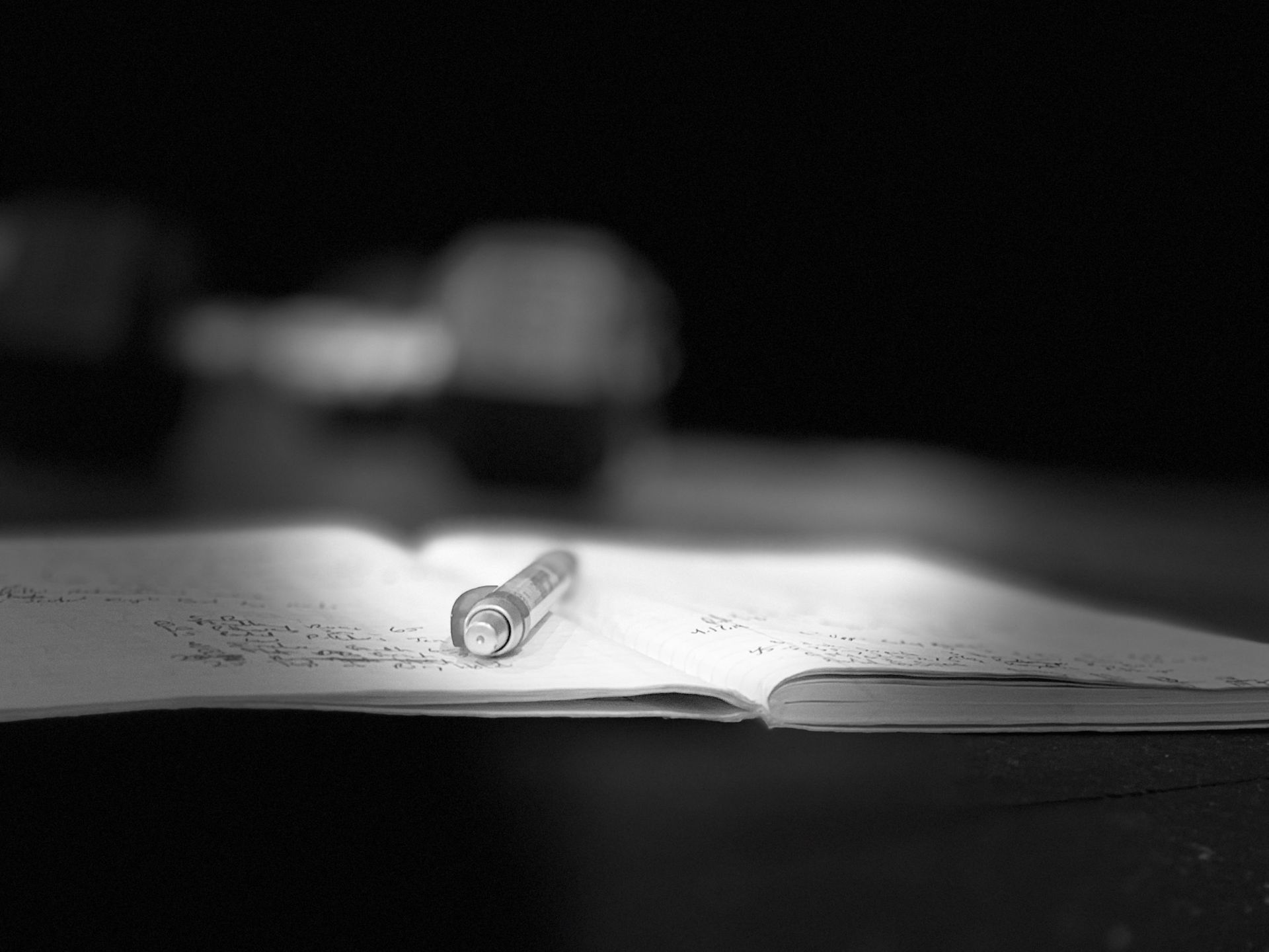 A pen is sitting on top of a notebook on a table.