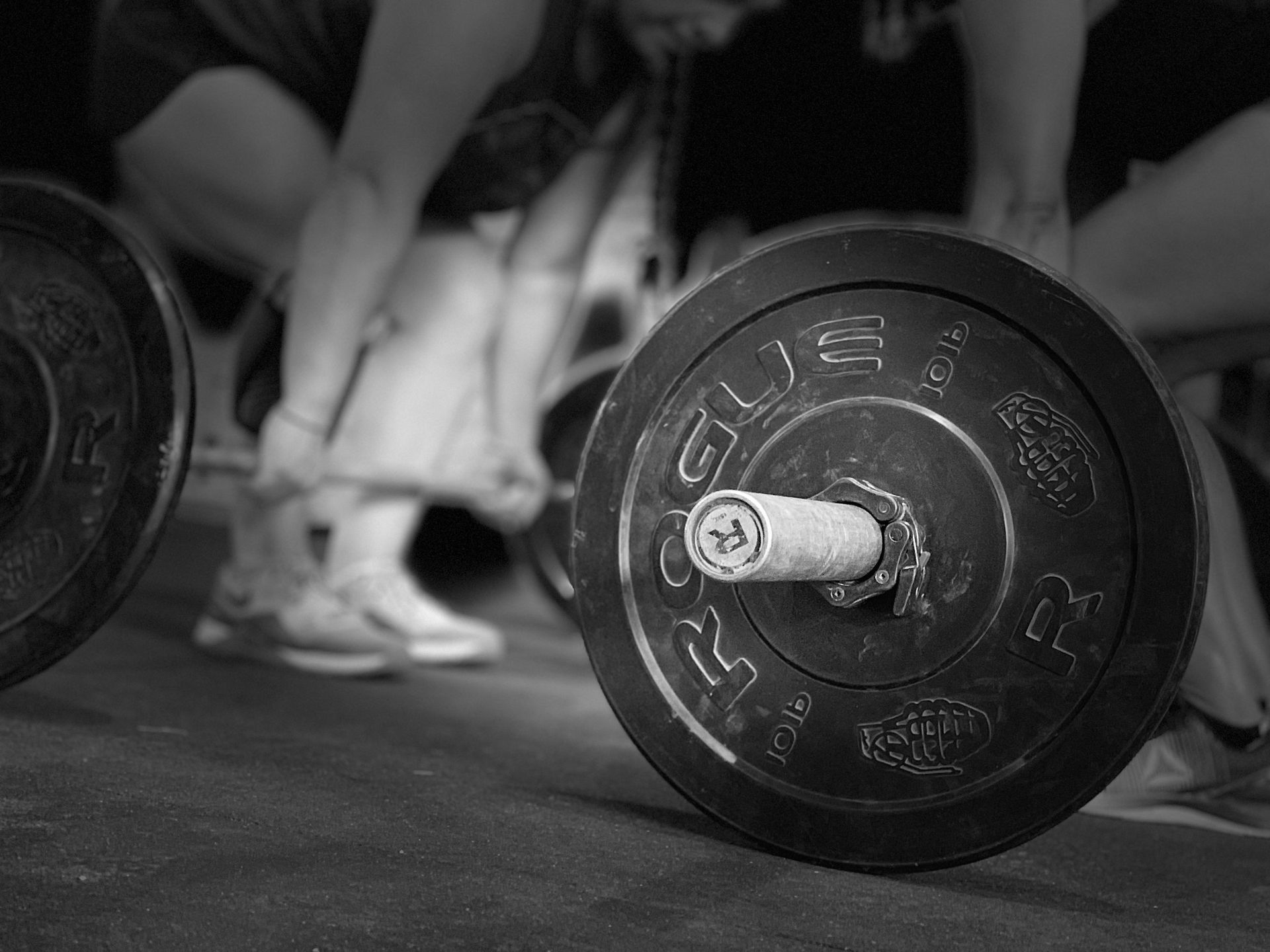 A black and white photo of a person lifting a barbell.