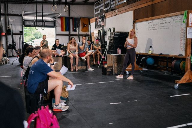 A woman is giving a presentation to a group of people in a gym.