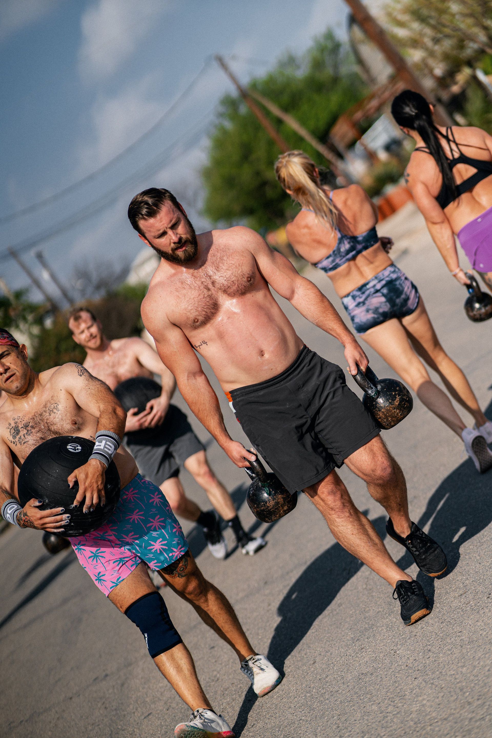 A group of people are walking down a street holding kettlebells.