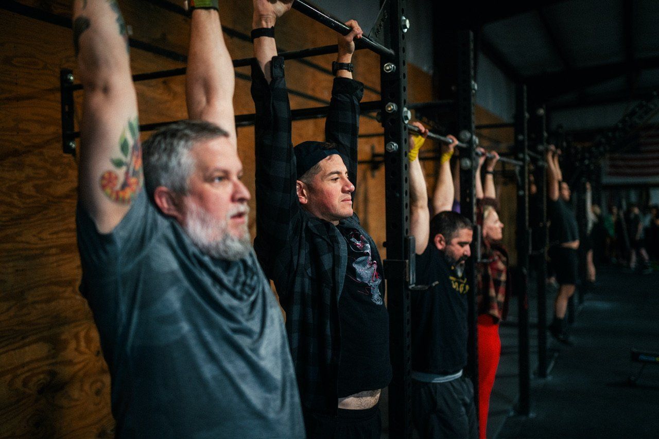 A group of men are doing pull ups in a gym.