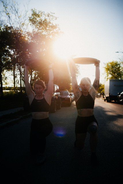 Two women are carrying a kettlebell over their heads.