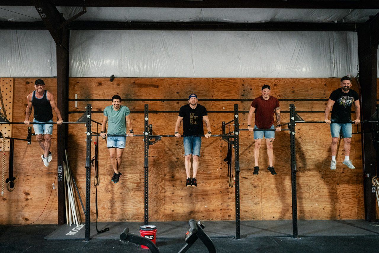 A group of men are doing pull ups on bars in a gym.