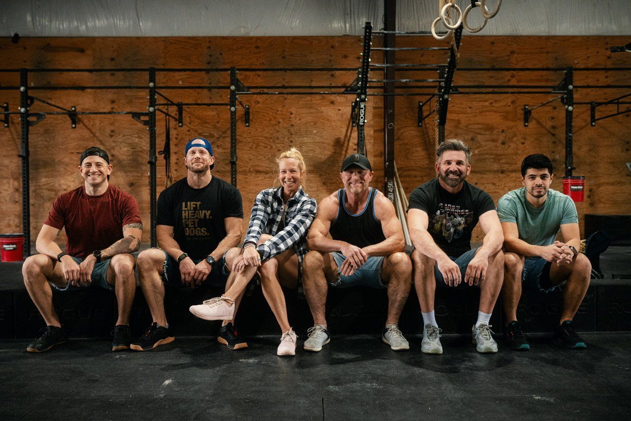 A group of people are sitting on a bench in a gym.