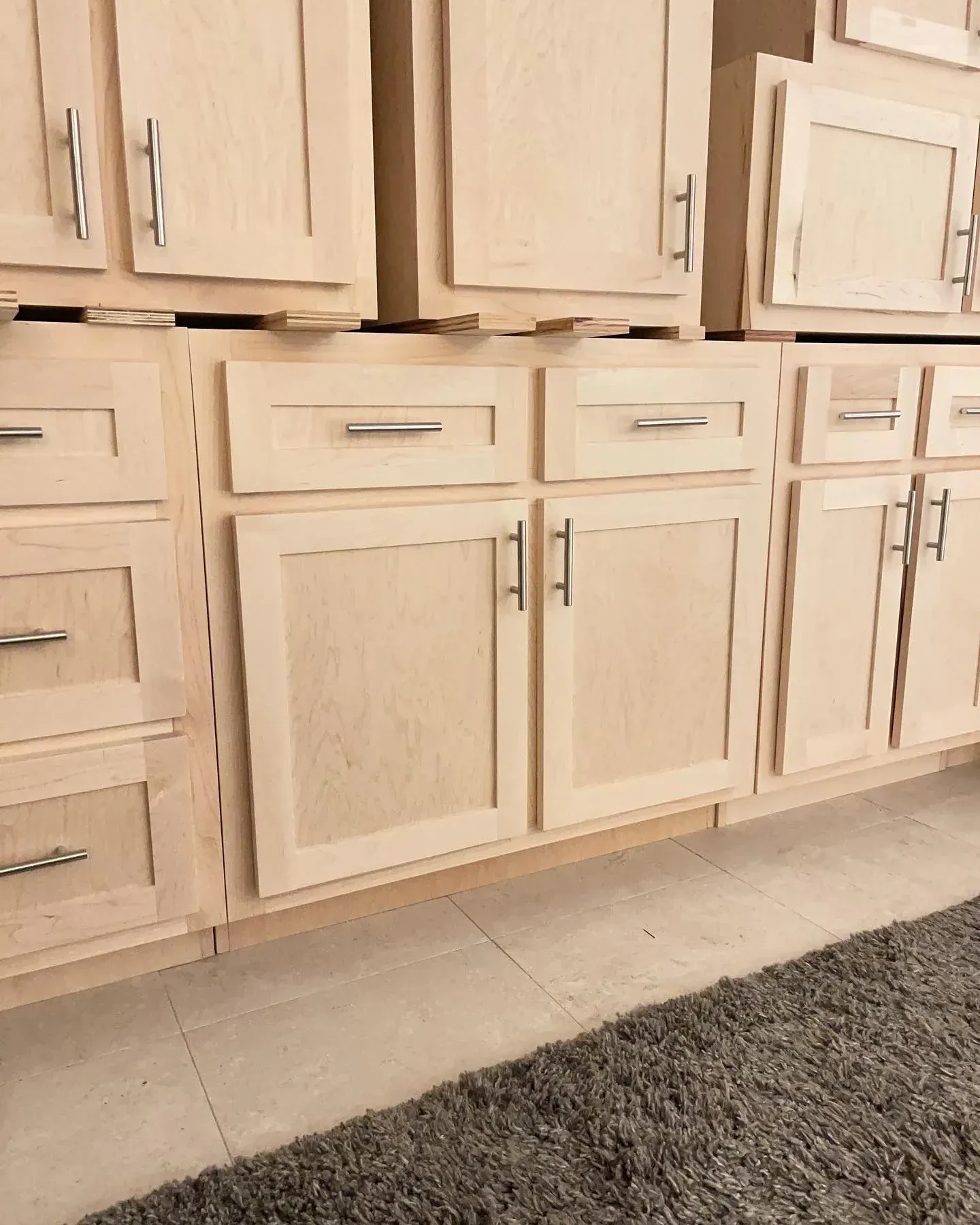 A kitchen with wooden cabinets and drawers and a rug on the floor