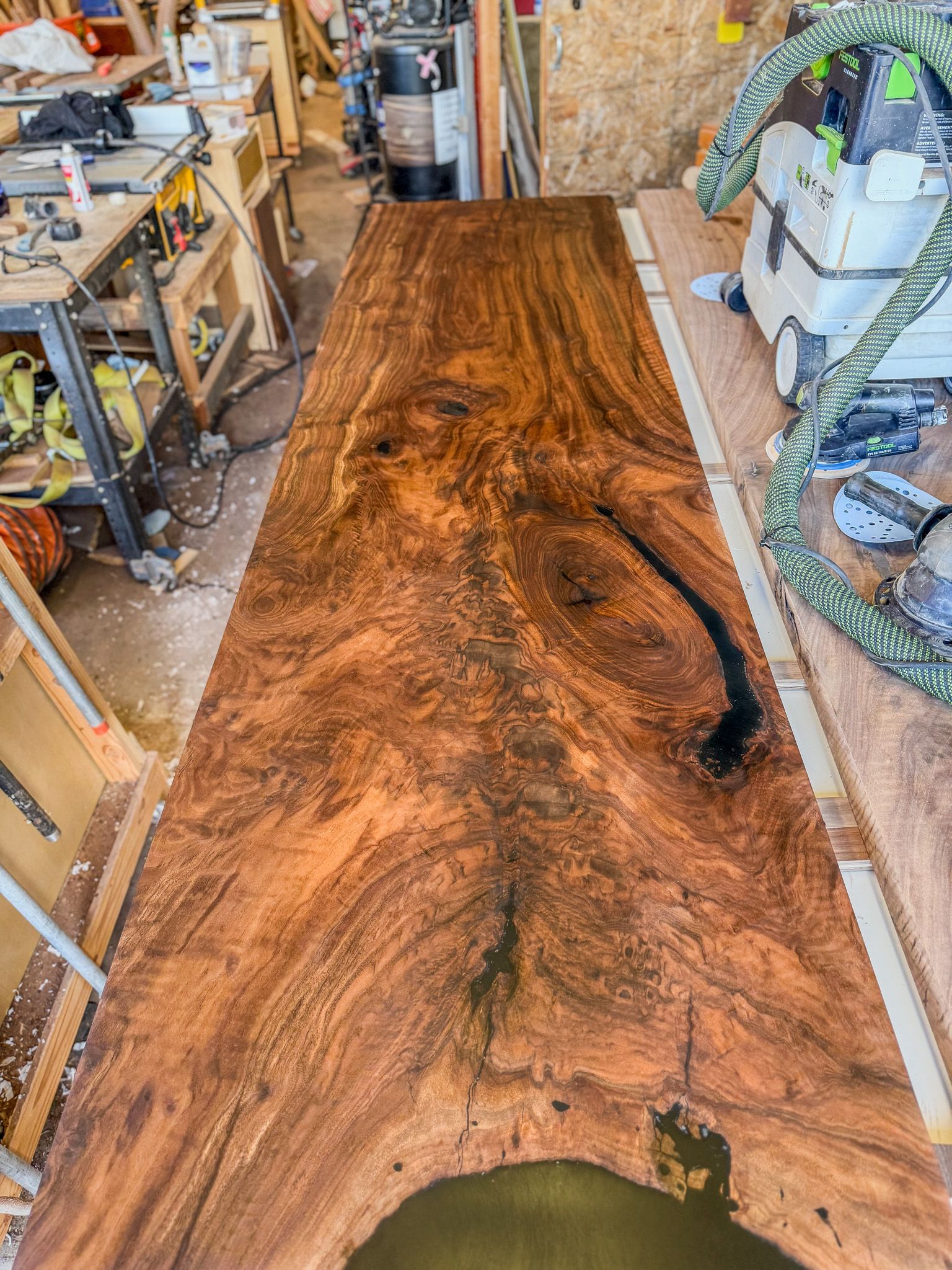 Long, brown wooden table with unique grain patterns, filled voids, and white epoxy edge.