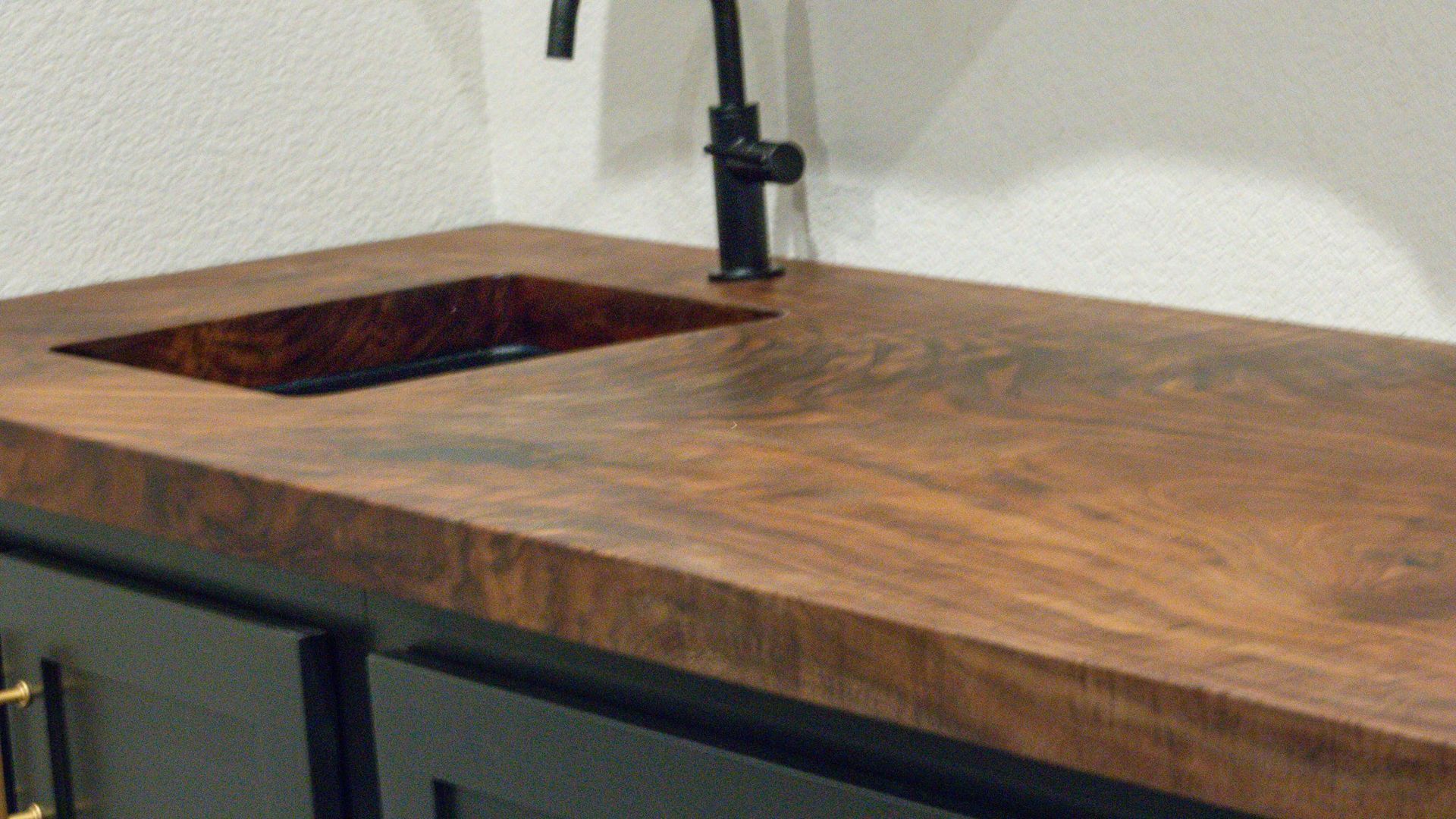 A wooden counter top with a sink and faucet on it.
