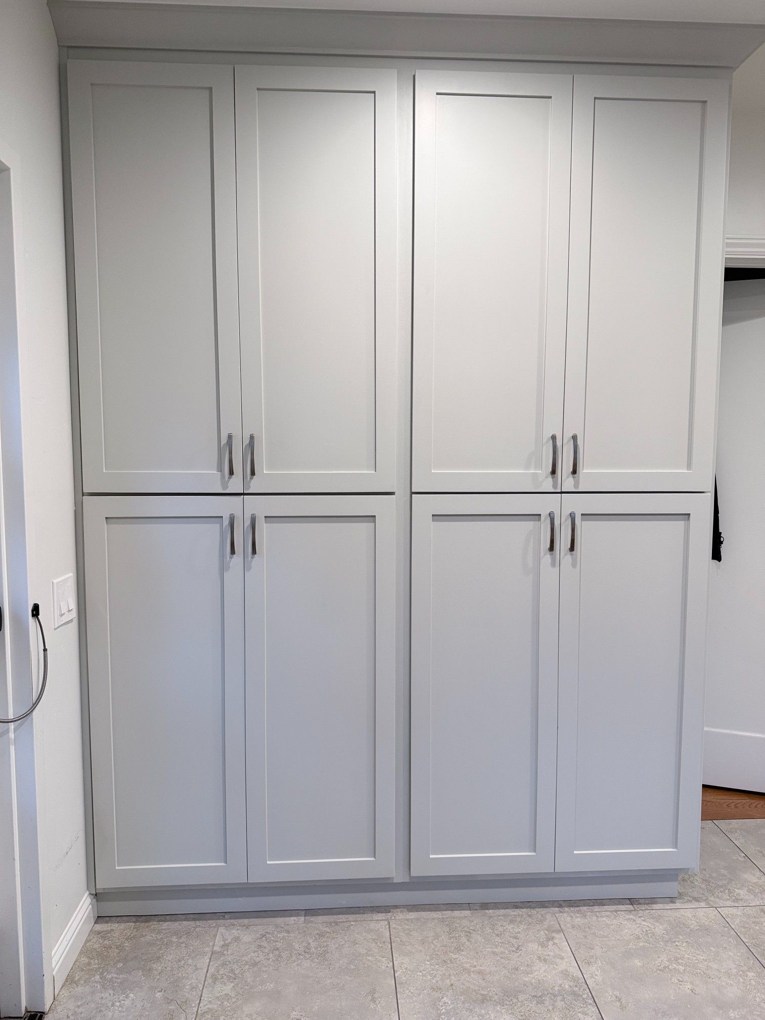 Tall, light gray storage cabinets against a wall, with four doors and dark handles.